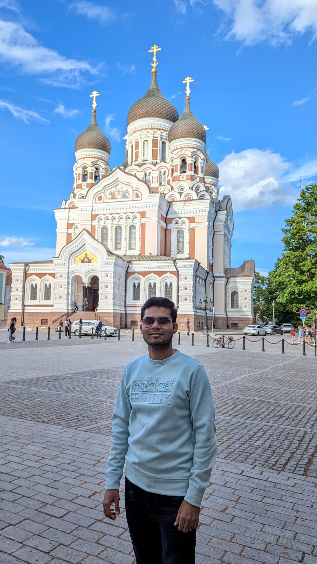 Shivam standing in front of the Alexander Nevsky Cathedral in Tallinn, with its ornate onion domes against a blue sky.